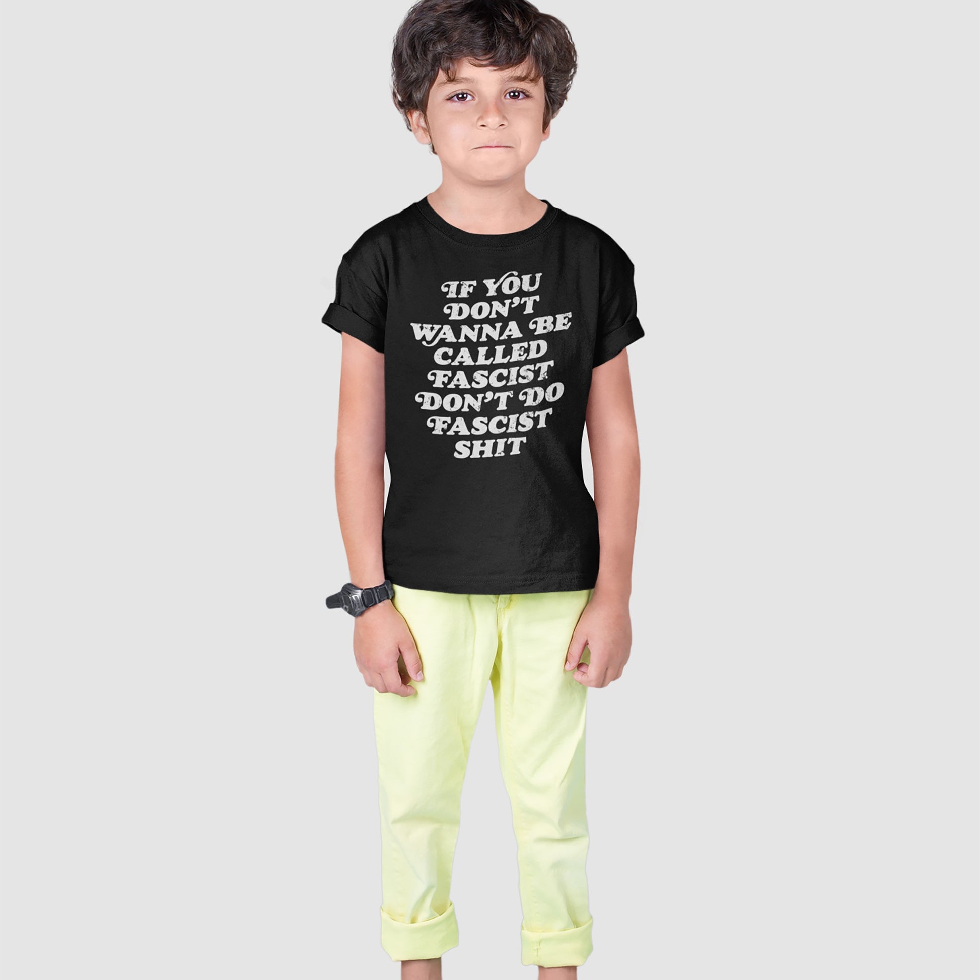 Young boy wearing the Anti-Fascist T-shirt displaying a bold message against fascism, paired with pale yellow pants and a wristwatch, embodying Egoproof's powerful, defiant statement apparel.