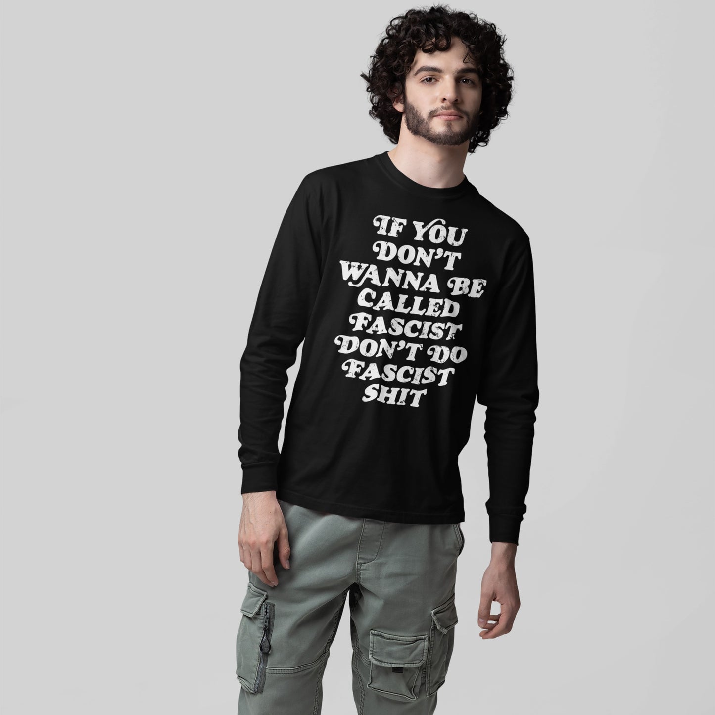 Young man models the Anti-Fascist T-shirt with bold slogan, advocating accountability. Paired with light-green cargo pants, this long-sleeve shirt embodies resistance and defiance, echoing Egoproof's empowering message.