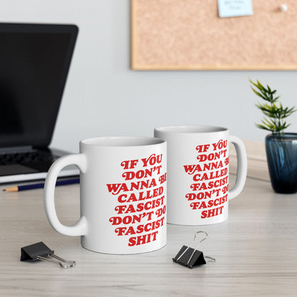 Anti-Fascist Mug with bold red slogan sits on a desk, surrounded by a laptop, pencil, binder clips, and a potted plant, embodying defiance and resistance in everyday life.
