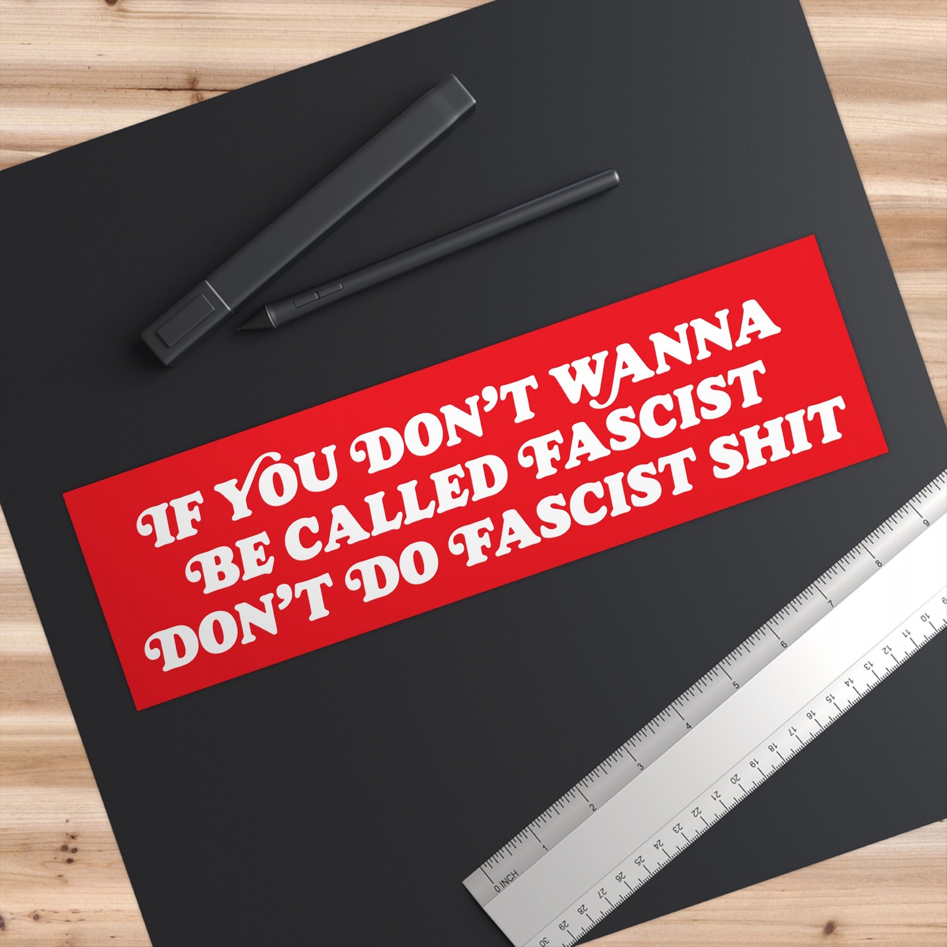 Anti-Fascist Sticker & Magnet on a designer's workspace with a drawing tablet, stylus, and ruler. The bold red design conveys a powerful, unapologetic message against oppression and fascism.