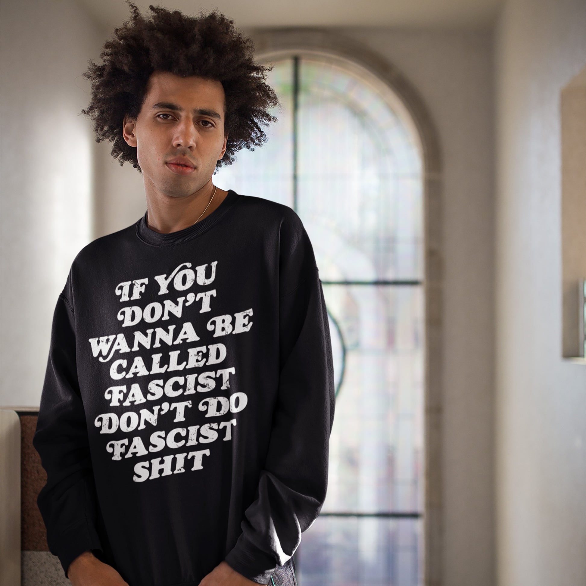 Young person in black sweatshirt with bold message: If you don’t wanna be called fascist don’t do fascist shit, showcasing the Anti-Fascist Hoodie & Sweatshirt from Egoproof.