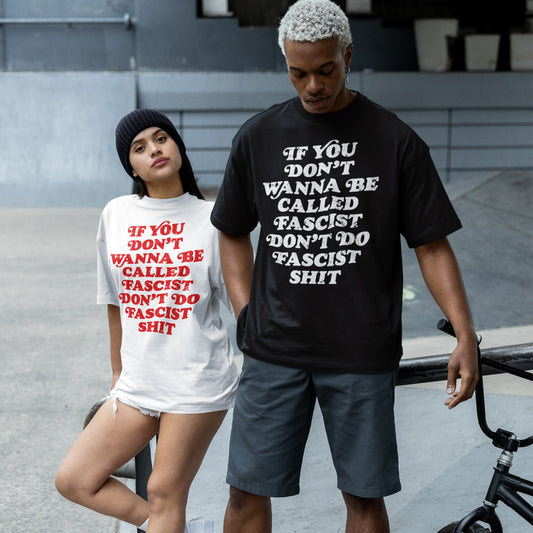 Two young adults in a skate-park wear Anti-Fascist T-shirts with a bold slogan, embodying Egoproof’s commitment to powerful, defiant statements. The woman leans on a rail, the man holds a BMX bike.