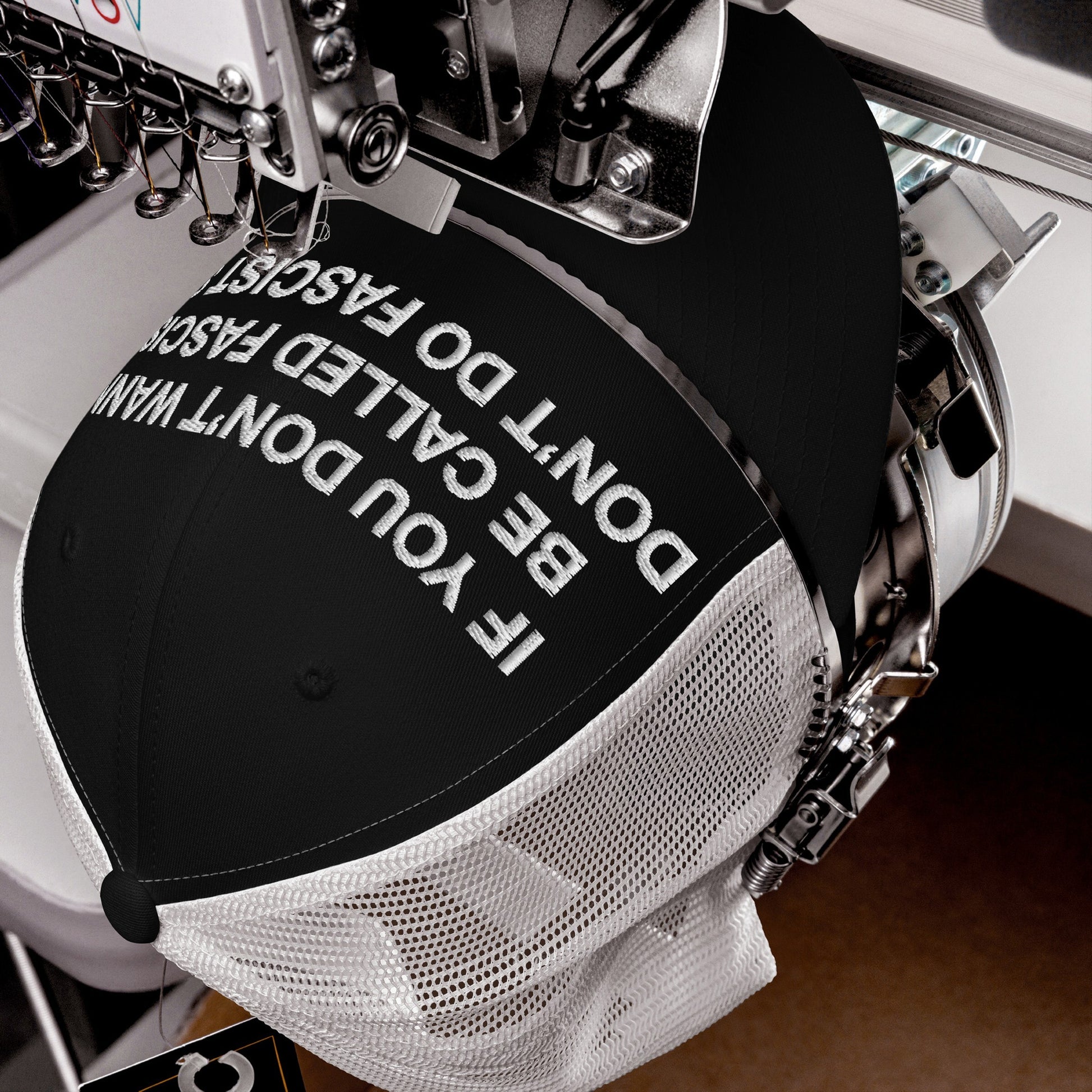 Anti-Fascist Hat in black-and-white mesh on an embroidery machine, featuring the bold slogan, IF YOU DON’T WANT TO BE CALLED FASCIST, DON’T DO FASCIST. Perfect for making a powerful everyday statement.