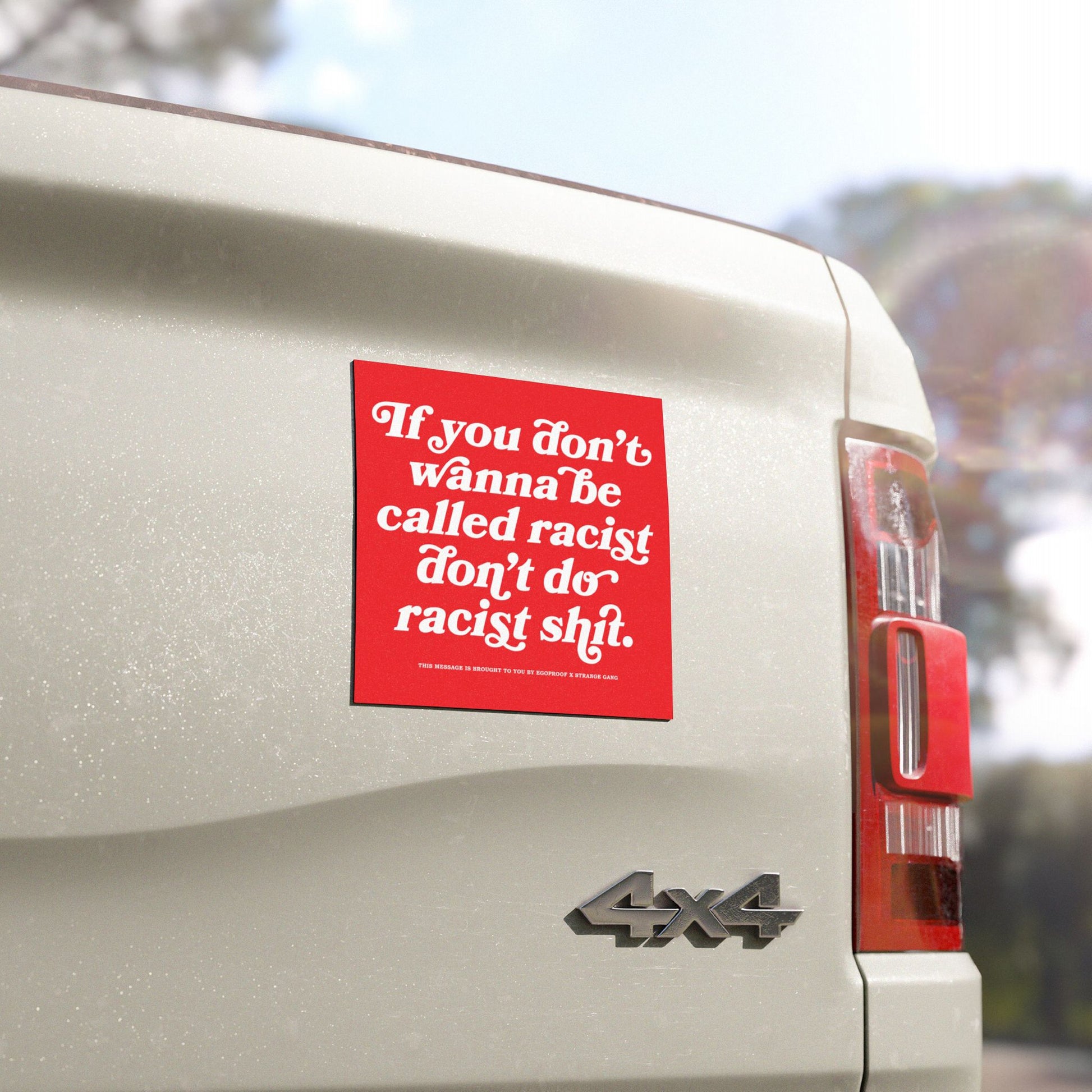 Anti-Racist Sticker & Magnet on a light-colored 4x4's rear, featuring bold red design with a clear message against racism. Taillight and 4x4 badge visible, highlighting its vibrant, impactful presence.