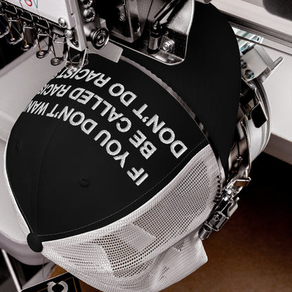 Black-front, white-mesh back trucker cap titled Anti-Racist Hat EU is in an embroidery machine, stitching IF YOU DON'T WANT TO BE CALLED RACIST, DON'T DO RACISM, reflecting a bold anti-racist statement.