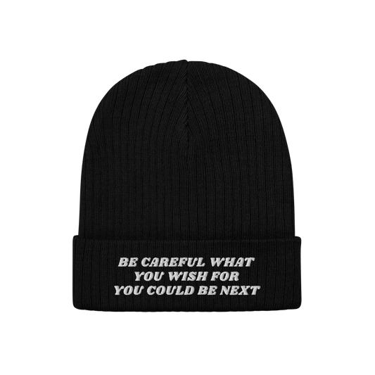 Black rib-knit beanie with folded-cuff, featuring white embroidered text BE CAREFUL WHAT YOU WISH FOR YOU COULD BE NEXT on fr