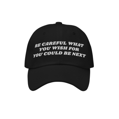 Black six-panel Be Careful Hat with a curved brim, featuring bold off-white embroidery: “BE CAREFUL WHAT YOU WISH FOR YOU C