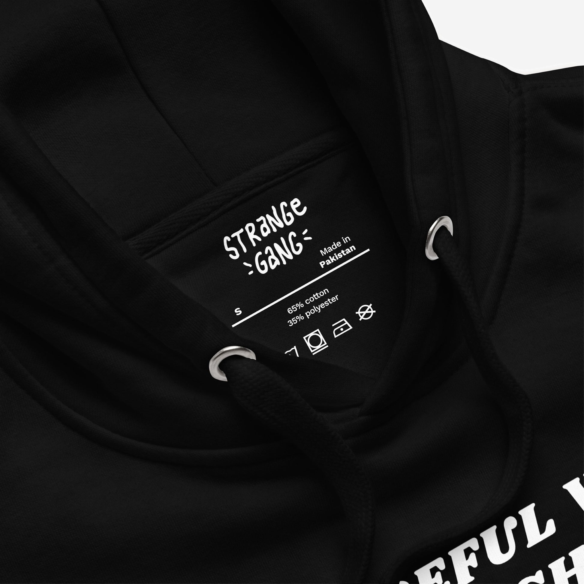 Be Careful Hoodie EU close-up shows neck details: brand name, Made in Pakistan label, size S, fabric content, care symbols, black drawstring, metal eyelets; embodies bold activism.