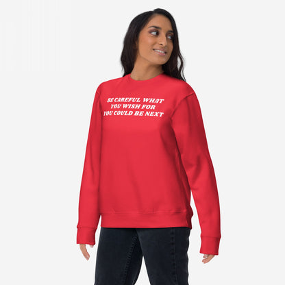 A woman wears the Be Careful Sweatshirt EU, featuring a bold anti-fascist message, perfect for activists and truth-tellers. The white text on the red crewneck delivers a powerful statement against injustice.