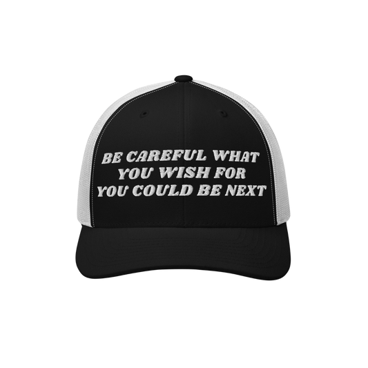 Black-and-white trucker-style baseball cap with BE CAREFUL WHAT YOU WISH FOR YOU COULD BE NEXT embroidered on the front. The 