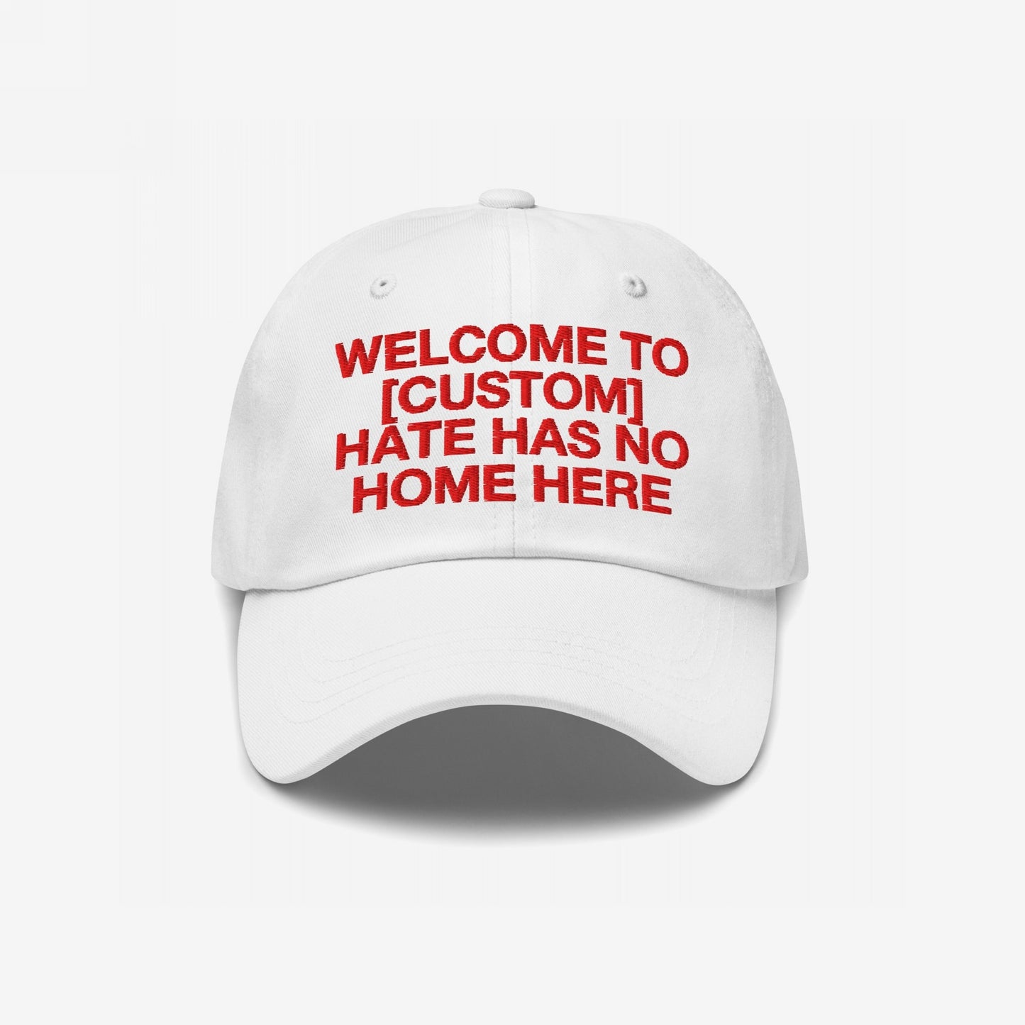 White Custom Hate Has No Home Here Dad Hat with red embroidered bold text promoting love and inclusivity, adjustable strap and classic fit.