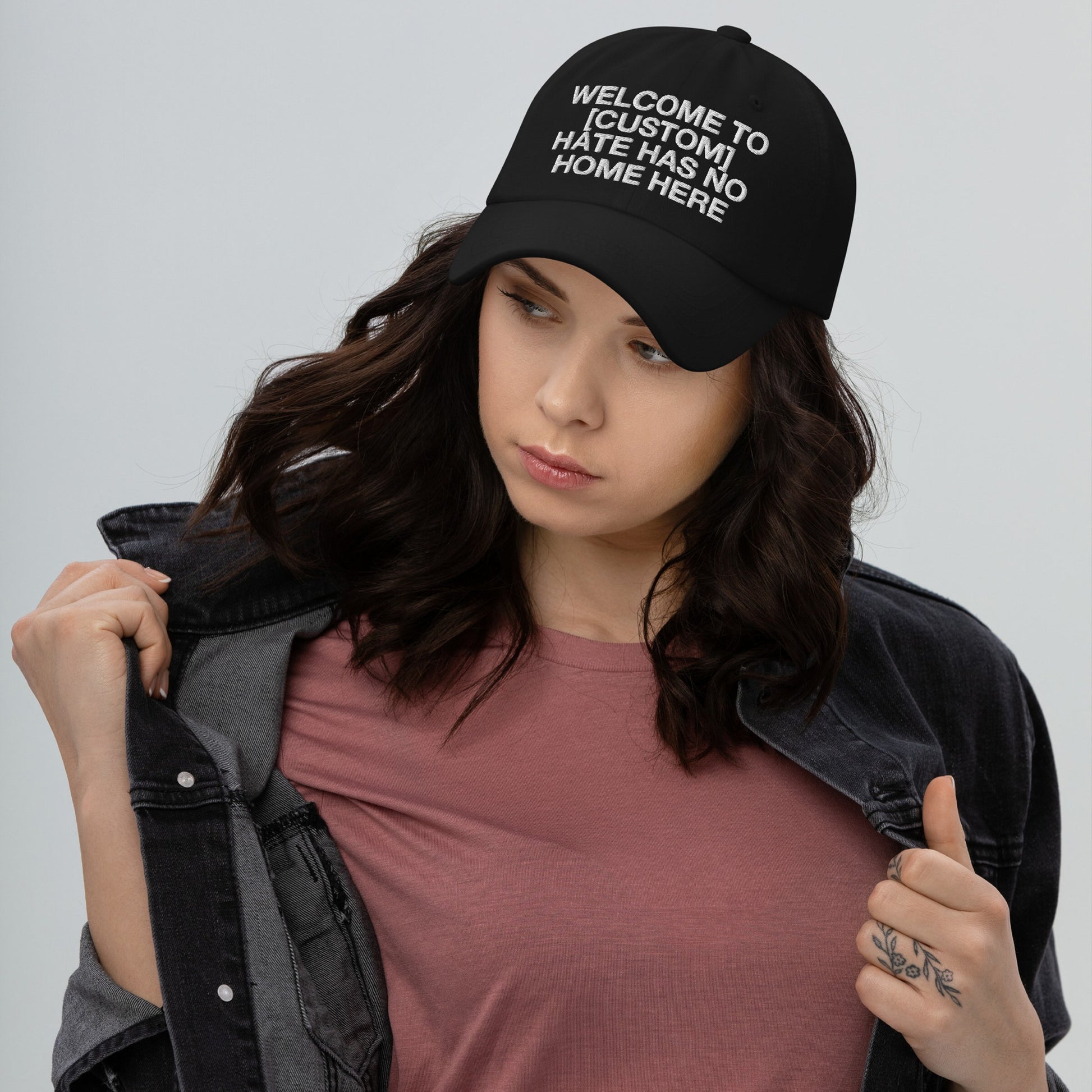 Woman wearing a black Custom Hate Has No Home Here Dad Hat with bold white embroidered message promoting love and acceptance