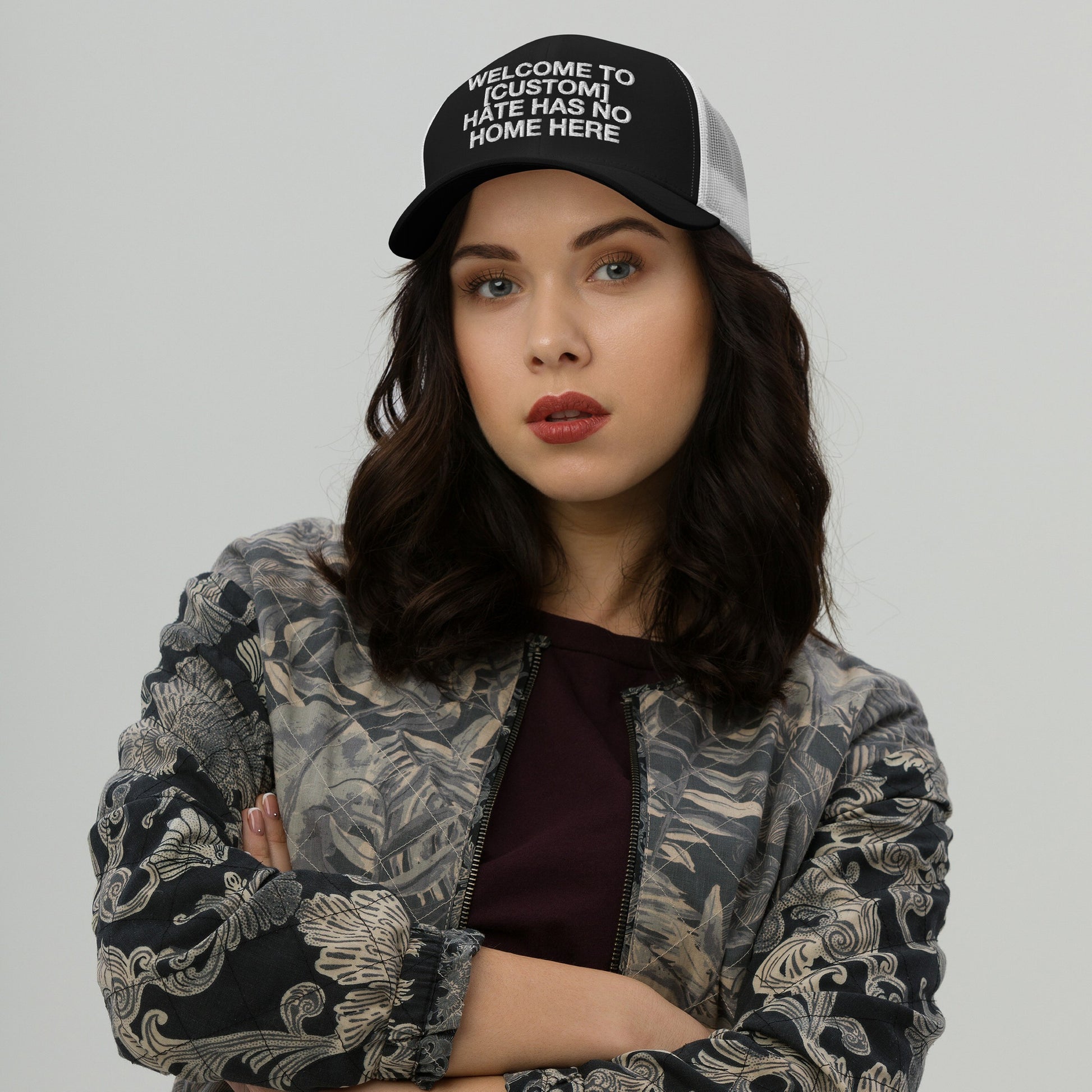 Woman wearing a Custom Hate Has No Home Here Trucker Hat with mesh back and adjustable snap closure in a bold message design