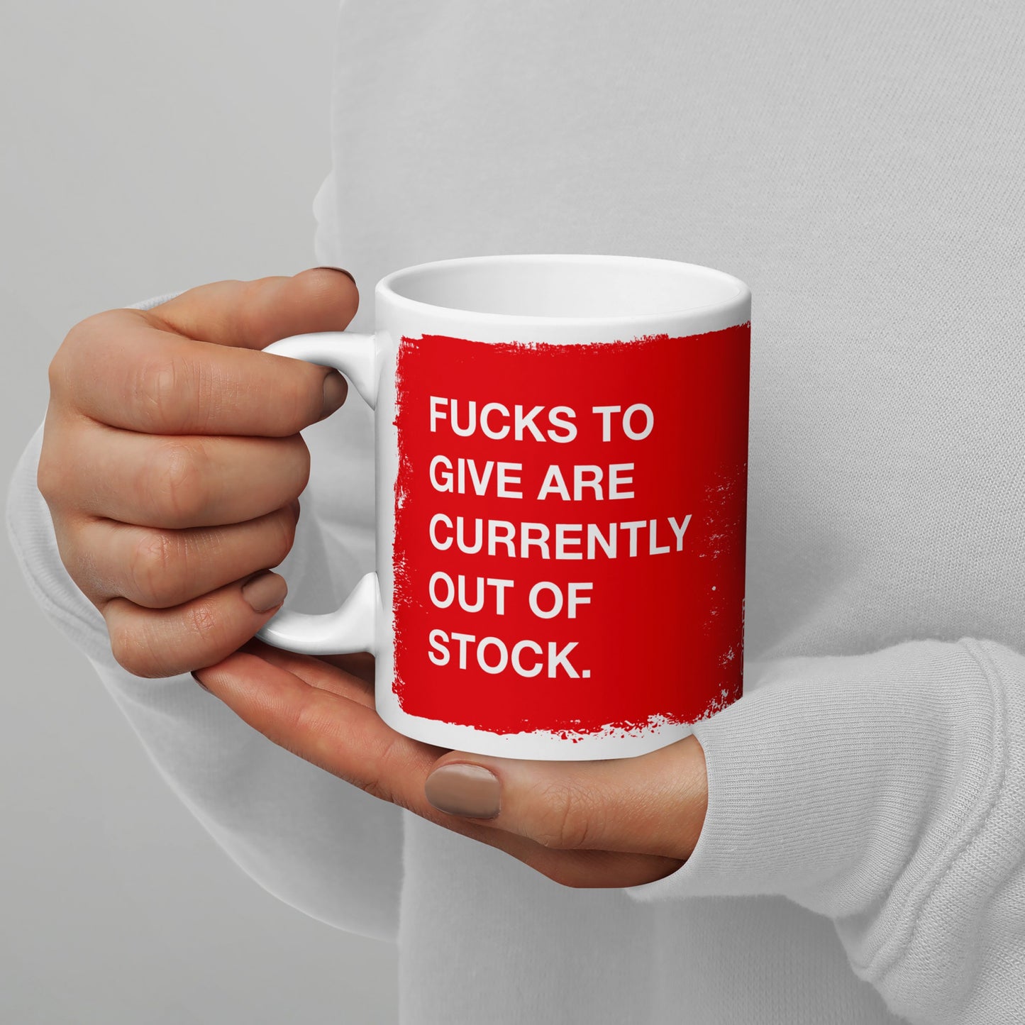 A person holds the Fucks To Give Mug, featuring bold white text on a red rectangle, humorously indicating an emotional inventory check. Perfect for expressing mental resilience with each sip.