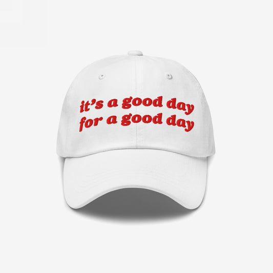 White baseball-style cap with red embroidered text reading “it’s a good day for a good day.” The Good Day Hat embodies positivity and retro style, supporting mental health advocacy through Egoproof's empowering ethos.