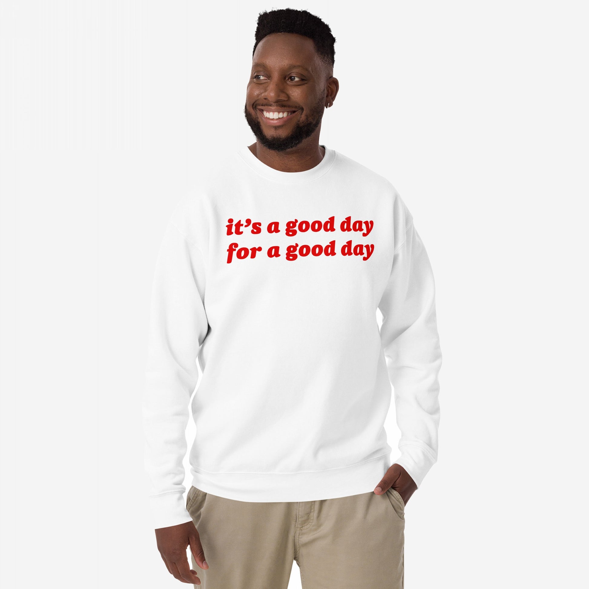 Smiling man wearing the Good Day Sweatshirt EU with bold red lettering, embodying comfort and optimism. Ideal for those embracing positivity and mental health awareness. Perfect for gifting or inspiring daily.