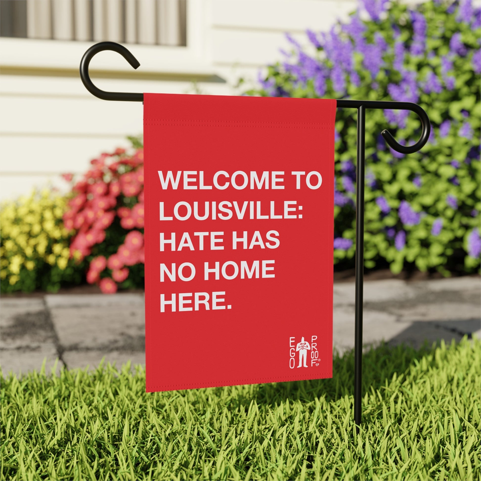 Custom Hate Has No Home Here Garden Flag staked in a lawn, featuring bold text welcoming to Louisville. The Egoproof logo is visible, embodying unity and acceptance.