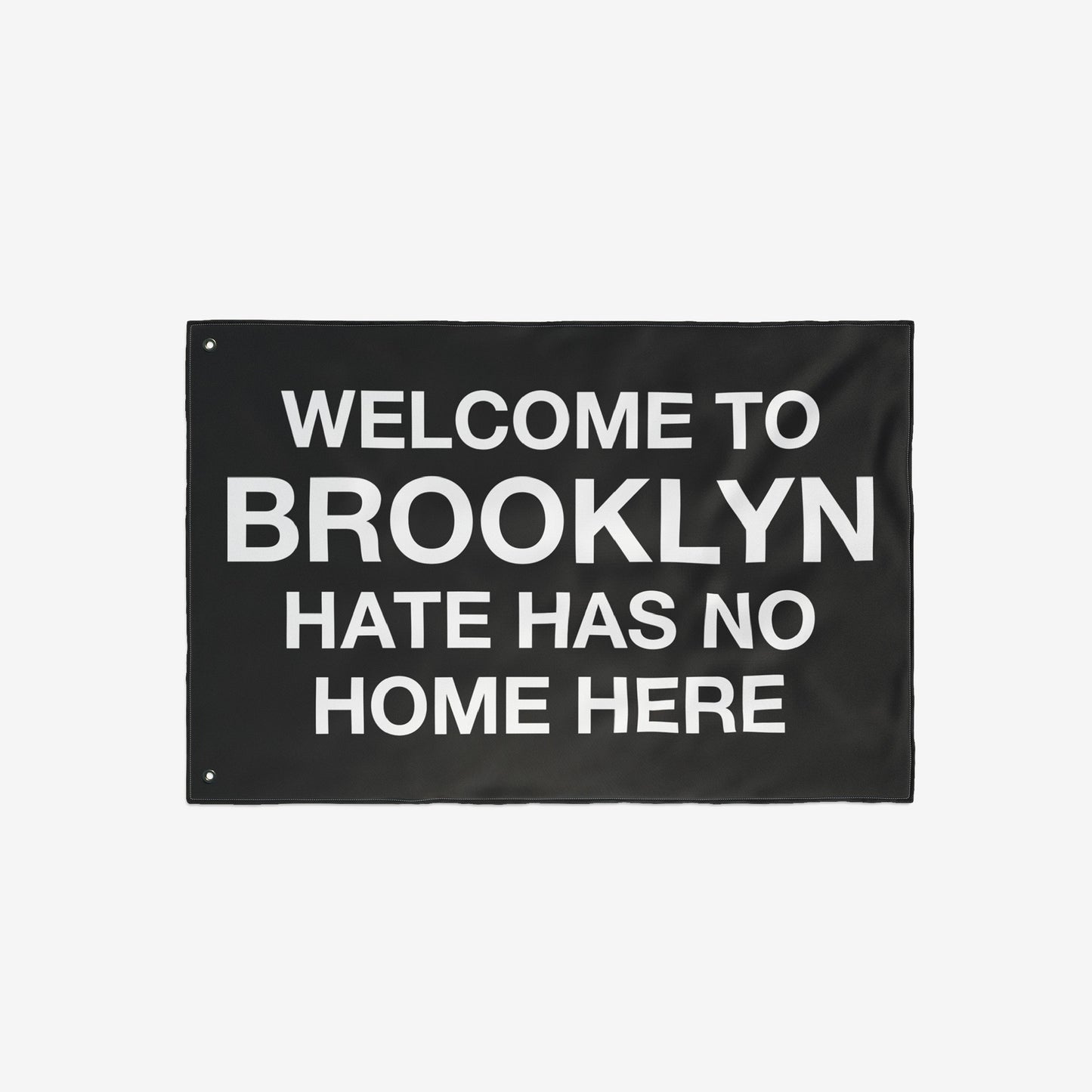 Custom Hate Has No Home Here Flag featuring bold, white text on a black background. Includes metal grommets for hanging. Ideal for showcasing unity and acceptance in various settings.