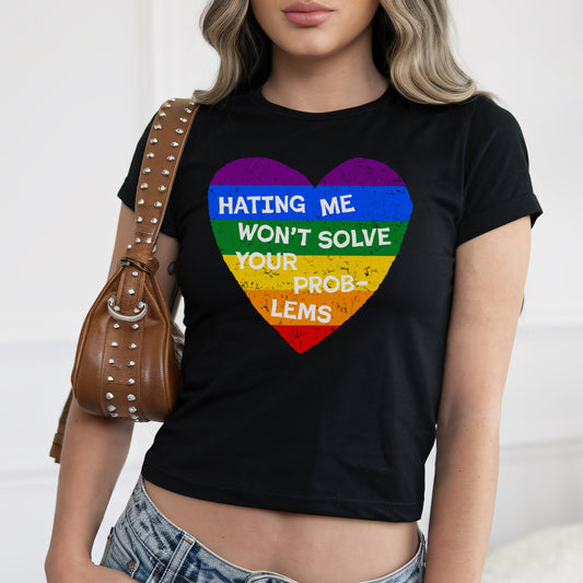 Woman wearing No LGBTQ Hate Women's Baby Tee black crop top with rainbow heart and slogan Hating Me Won't Solve Your Problems.
