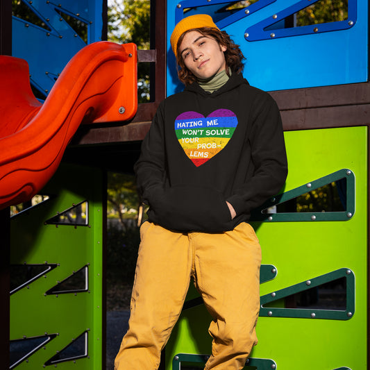 Person wearing No LGBTQ Hate Hoodie with rainbow heart and quote "Hating me won't solve your problems" at colorful playground.