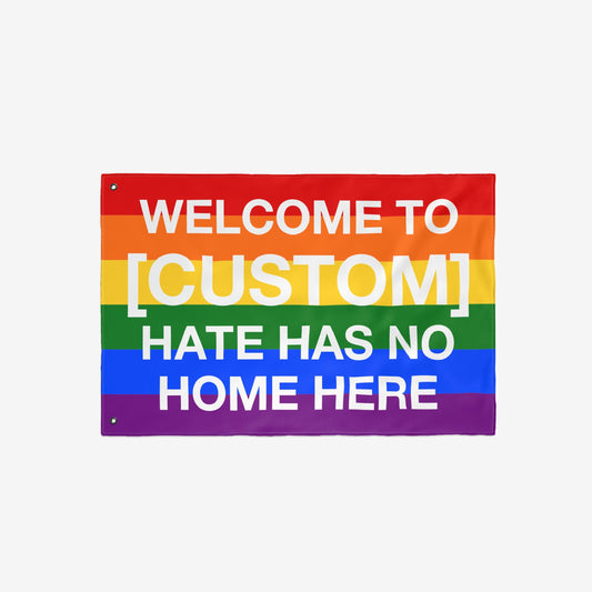 Custom Hate Has No Home Here Pride Flag with rainbow stripes, customizable text space, and grommets for hanging. Promotes inclusivity and LGBTQ+ acceptance, available in various sizes.