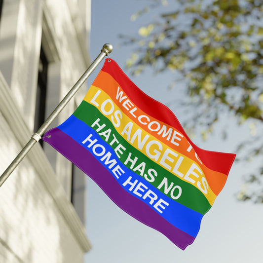 Custom Hate Has No Home Here Pride Flag with rainbow stripes and bold text, mounted on a pole, exemplifying inclusivity and LGBTQ+ acceptance. Ideal for personalizing with your city name.