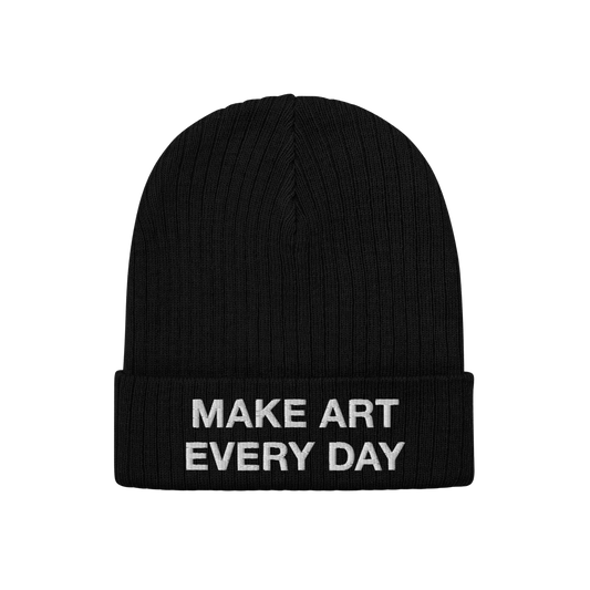 Make Art Every Day Beanie shows a black knitted cuff-style hat with the phrase “MAKE ART EVERY DAY” embroidered in white,