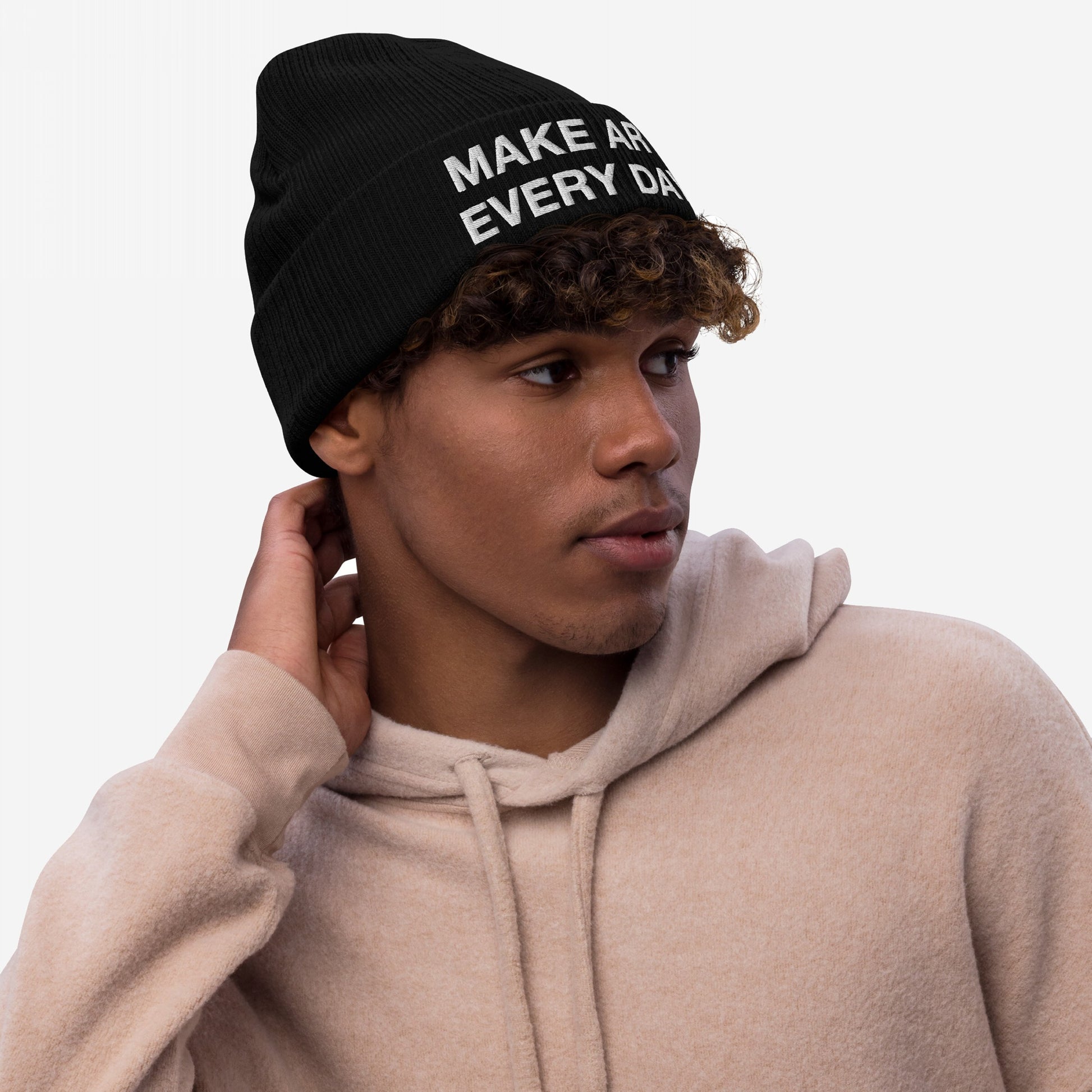 Young man wearing a Make Art Every Day knit beanie, showcasing its embroidered slogan. The hat's design embodies creativity and persistence, aligning with Egoproof's mission of powerful, everyday statements.
