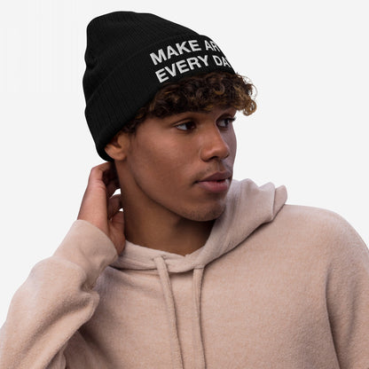 Young man wearing a Make Art Every Day knit beanie, showcasing its embroidered slogan. The hat's design embodies creativity and persistence, aligning with Egoproof's mission of powerful, everyday statements.