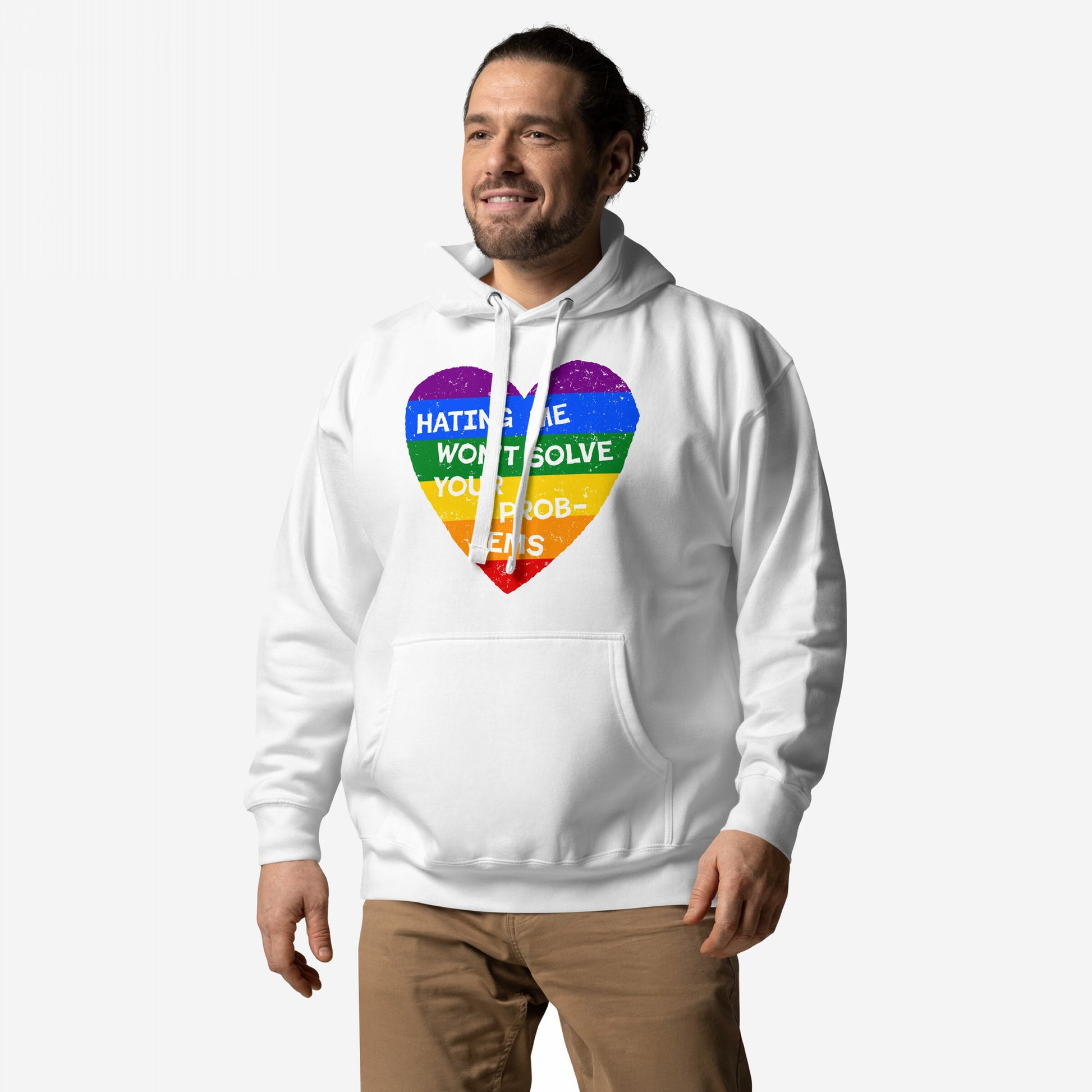 No LGBTQ Hate Hoodie EU features a rainbow heart with Hating Me Won’t Solve Your Problems slogan, worn by a smiling man, embodying pride and resilience against a light background.