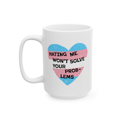 The No Trans Hate Mug features a pastel-striped heart with the phrase “Hating Me Won’t Solve Your Problems” printed on 