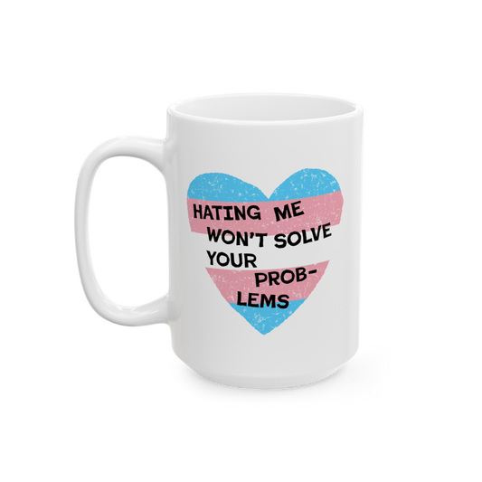 The No Trans Hate Mug features a pastel-striped heart with the phrase “Hating Me Won’t Solve Your Problems” printed on 