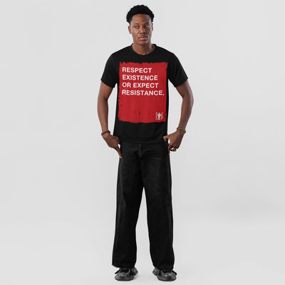 Young man in a Respect Existence T-shirt, featuring a bold red square with a powerful slogan. He pairs it with loose black jeans and sneakers, embodying resistance and awareness.