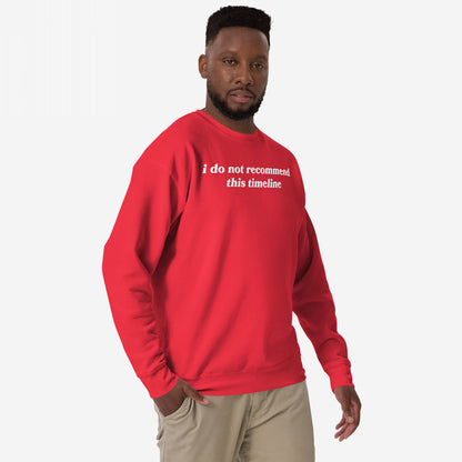 Black man models the Timeline Sweatshirt EU, featuring the statement i do not recommend this timeline. Paired with khaki pants, this midweight crewneck captures humor and burnout awareness.