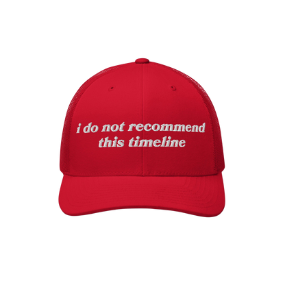 Timeline Hat: Bright red trucker-style cap with i do not recommend this timeline. embroidered in white; embodies sarcasm and 